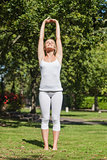 Front view of content young woman stretching her arms in a park