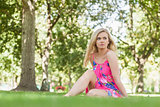 Beautiful woman wearing a dress sitting on a lawn
