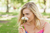 Lovely blonde woman smelling a flower