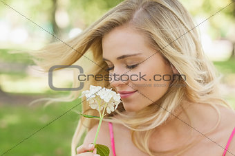 Gorgeous content woman smelling a flower with closed eyes