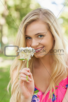Pretty young woman smelling a white flower