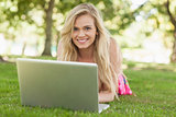 Peaceful attractive woman using her notebook lying on a lawn