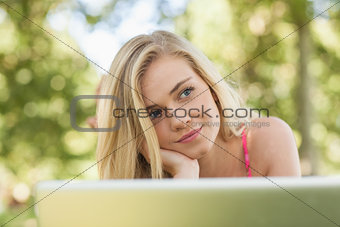 Day dreaming attractive woman lying in front of her notebook
