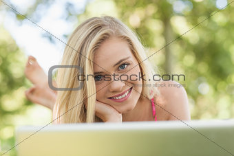 Joyful young woman lying in front of her notebook