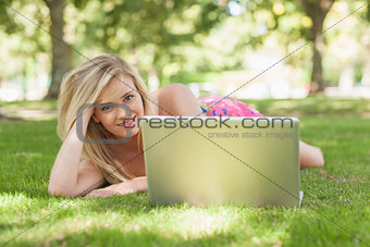 Beautiful blonde woman posing lying on a lawn