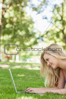Profile view of cute blonde woman using her notebook