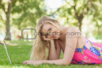 Portrait of gorgeous woman using her notebook lying on a lawn