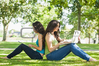 Two young brunette women sitting on a lawn