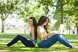 Young brunette woman sitting with her friend on a lawn