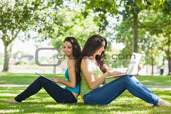 Young brunette woman sitting with her friend on a lawn