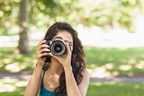 Front view of cute brunette woman taking a picture with her camera