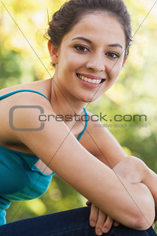 Side view of young brunette woman sitting on a lawn