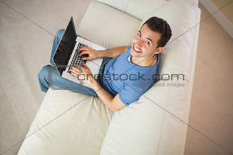 High angle view of casual smiling man using laptop