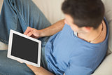 High angle view of casual man using tablet sitting on couch