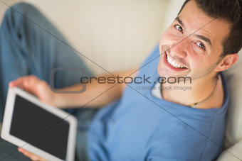 High angle view of casual smiling man using tablet sitting on couch