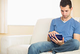 Casual calm man using tablet sitting on couch
