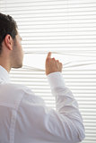 Rear view of attractive businessman spying through roller blind