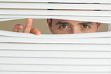 Focused male eyes spying through roller blind