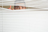 Shocked male eyes spying through roller blind