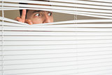 Scared male eyes spying through roller blind
