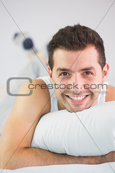Cheerful handsome man lying in bed looking at camera