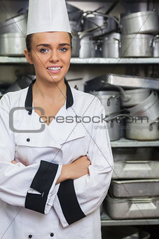 Young gorgeous chef standing arms crossed between shelves