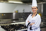 Young smiling chef standing arms crossed in front of hotplate