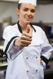 Young happy chef looking at camera showing thumb up