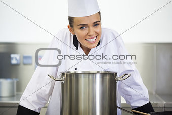 Young smiling chef standing behind saucepan