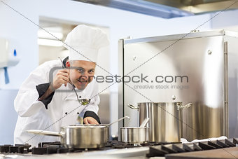 Smiling head chef tasting food from ladle