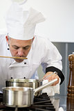 Concentrating head chef tasting sauce with wooden spoon
