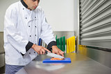 Chef cutting raw salmon with knife on blue cutting board