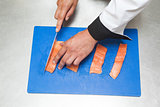 Chef slicing raw salmon with sharp knife