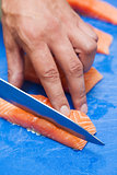 Close up of hand slicing salmon with sharp knife