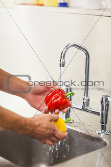 Kitchen porter washing vegetable under running tap