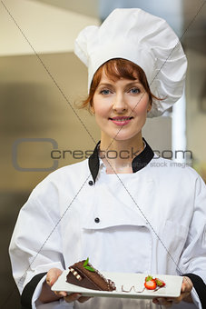 Pretty smiling chef presenting chocolate cake with strawberries