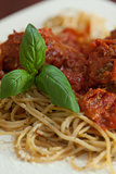 Close up of spaghetti and meatballs with basil leaf