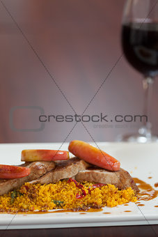 Front view of couscous dish with meat and red wine