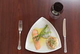 Overhead view of salmon dish with asparagus and red wine