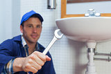 Handsome smiling plumber showing wrench