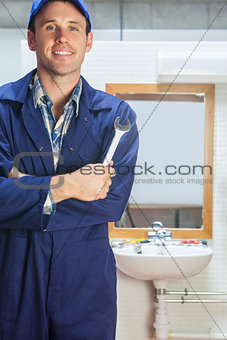 Smiling plumber posing with wrench