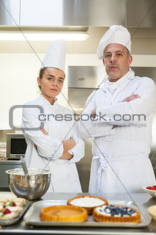 Frowning chef and head chef standing arms crossed