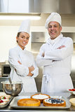 Smiling chef and head chef standing arms crossed