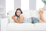 Portrait of pretty brunette woman lying on her couch in the living room