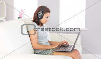 Concentrated casual woman working with her notebook while listening to music