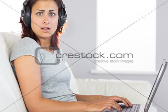 Surprised brunette woman working with her notebook and listening to music