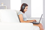 Focused attractive woman using her notebook and listening to music