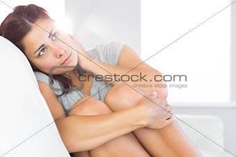 Melancholic gorgeous woman sitting on her couch