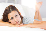 Melancholic young woman lying on her white couch