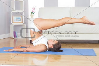 Sporty slim woman doing yoga pose on blue exercise mat